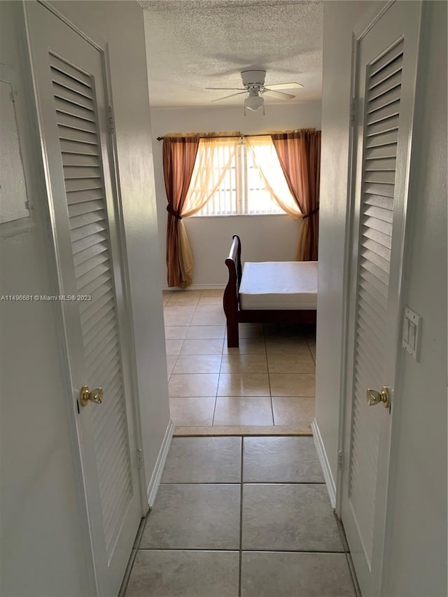 unfurnished bedroom with ceiling fan, light tile patterned floors, and a textured ceiling