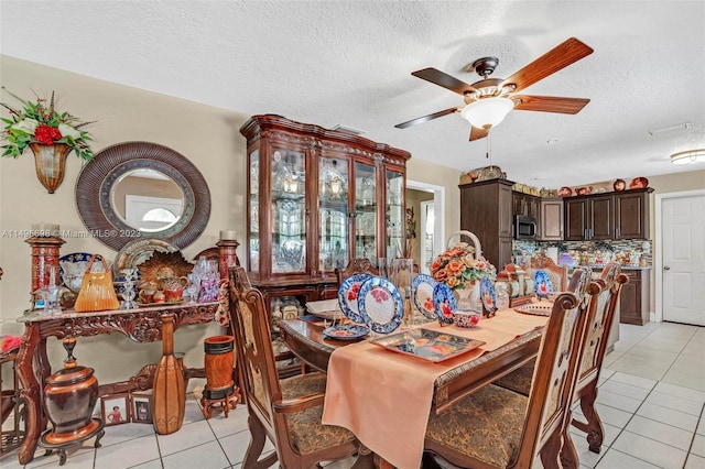 dining space with a textured ceiling, light tile patterned floors, and ceiling fan