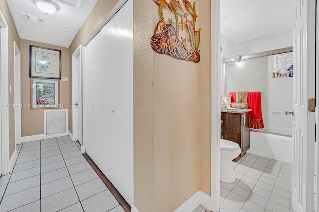 hallway featuring light tile patterned flooring and a textured ceiling