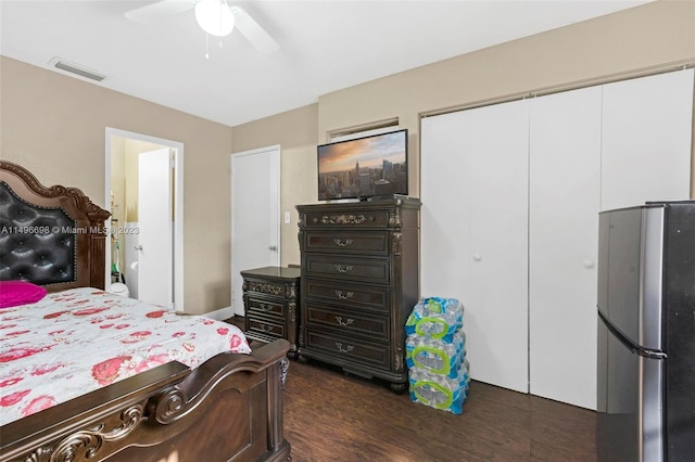 bedroom with a closet, dark hardwood / wood-style flooring, stainless steel refrigerator, and ceiling fan