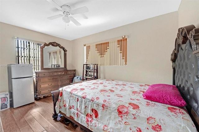 bedroom featuring hardwood / wood-style floors, ceiling fan, and white refrigerator