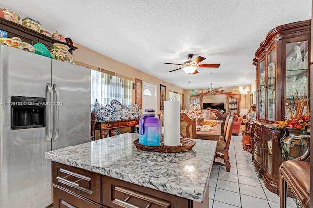 kitchen featuring light tile patterned flooring, a textured ceiling, ceiling fan, stainless steel fridge, and dark brown cabinetry