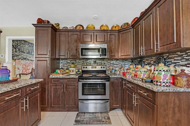 kitchen featuring light tile patterned flooring, light stone counters, stainless steel appliances, and backsplash