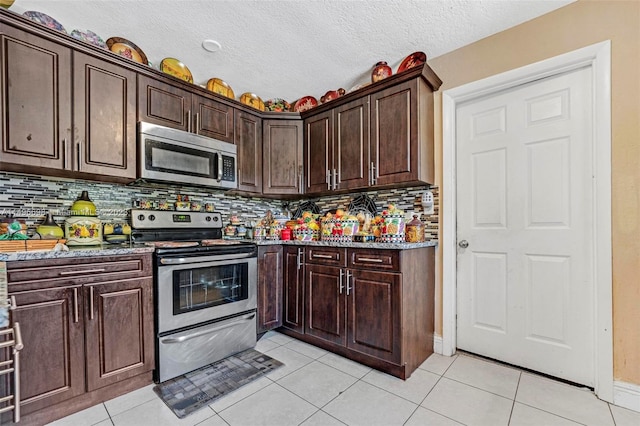 kitchen with light tile patterned flooring, stainless steel appliances, light stone counters, and tasteful backsplash