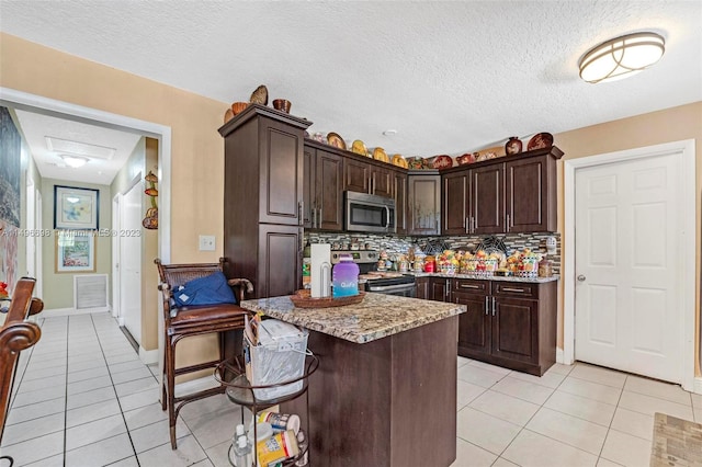 kitchen with dark brown cabinets, tasteful backsplash, appliances with stainless steel finishes, and light tile patterned floors