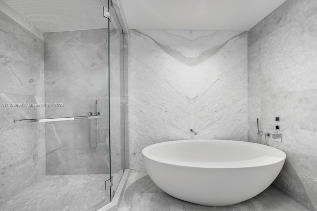 bathroom featuring tile patterned flooring, tile walls, and plus walk in shower