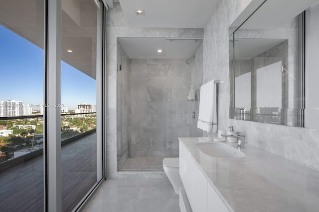 bathroom with tiled shower, tile patterned flooring, toilet, vanity, and tile walls