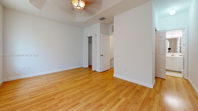 unfurnished bedroom with ensuite bathroom, sink, and light wood-type flooring