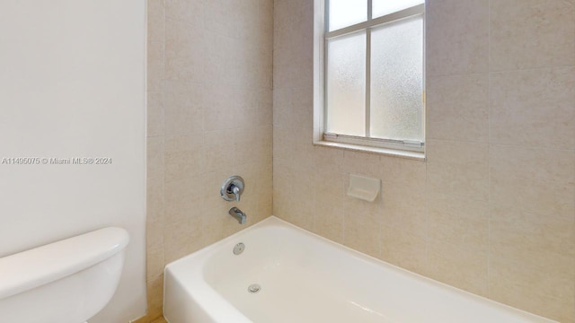 bathroom featuring toilet and tiled shower / bath