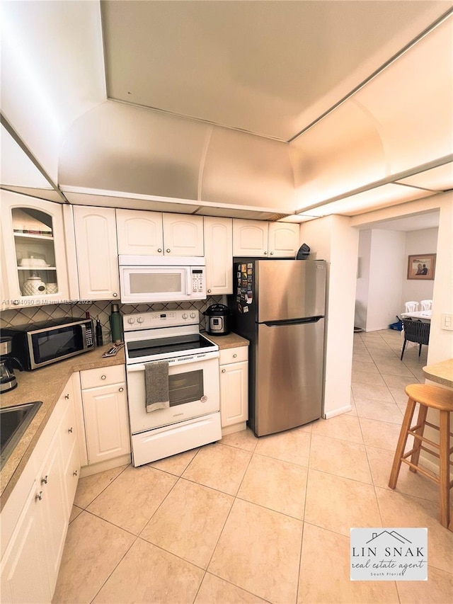 kitchen featuring tasteful backsplash, white cabinets, stainless steel appliances, and light tile patterned floors