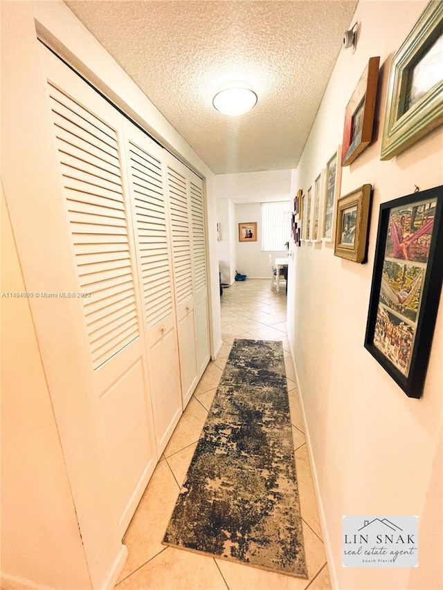 hallway with light tile patterned floors and a textured ceiling