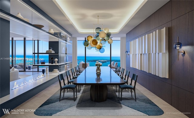 dining space featuring a notable chandelier, a water view, and a tray ceiling