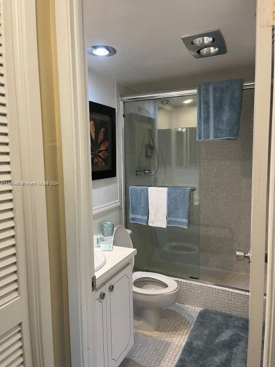 bathroom with toilet, an enclosed shower, tile patterned floors, and vanity