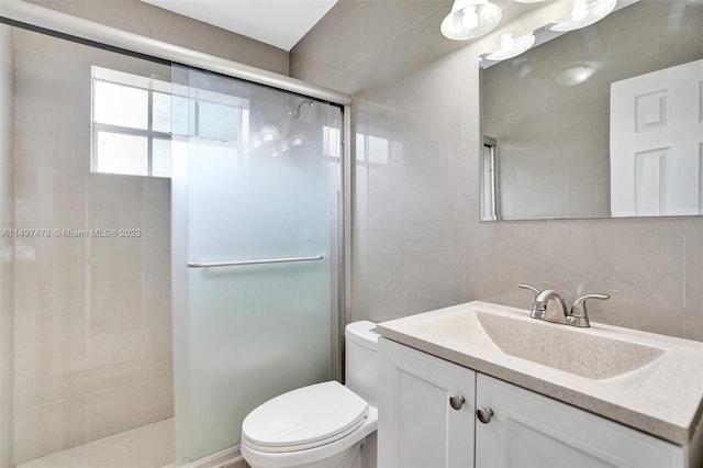 bathroom featuring toilet, large vanity, a shower with door, tasteful backsplash, and tile walls