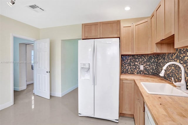 kitchen with sink, backsplash, butcher block countertops, white fridge with ice dispenser, and light brown cabinets