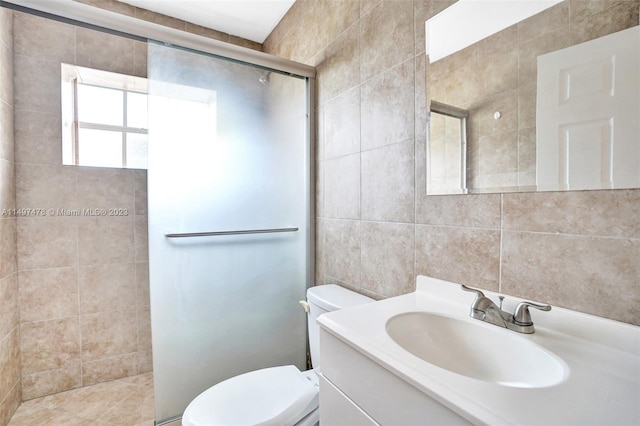 bathroom featuring toilet, a shower with shower door, vanity, and tile walls