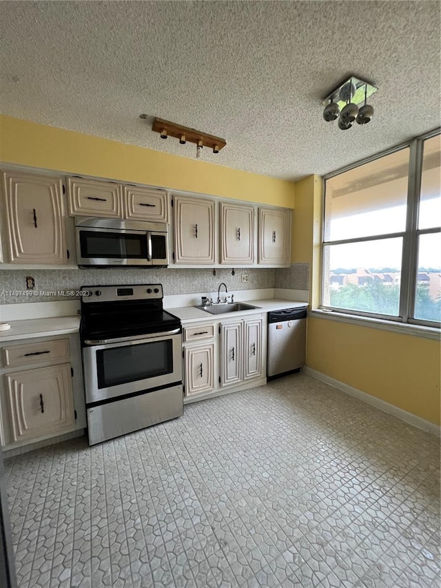 kitchen with sink, a textured ceiling, and appliances with stainless steel finishes