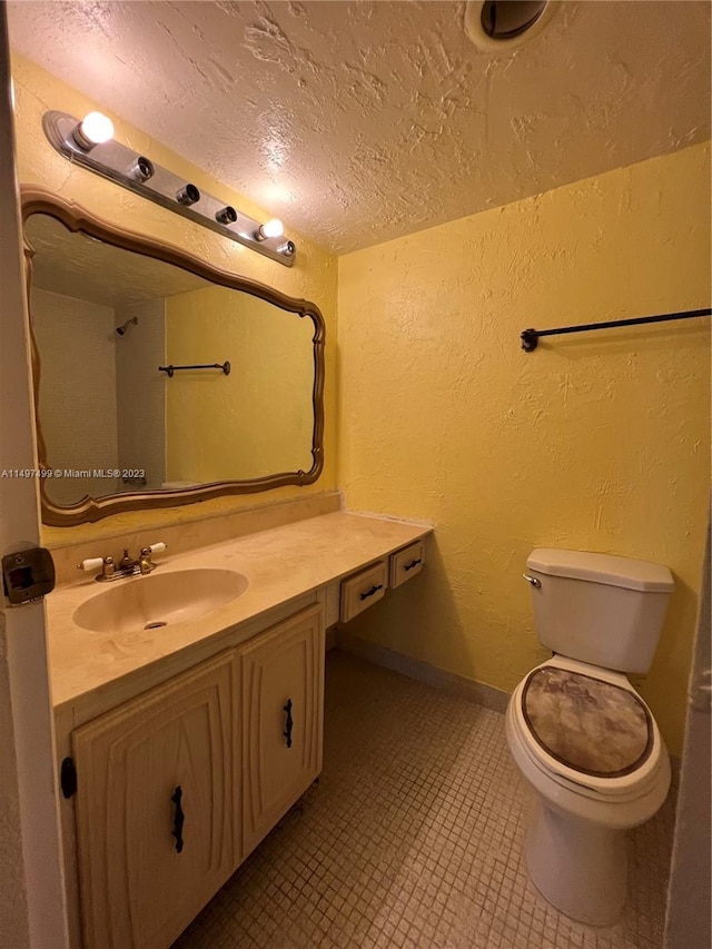 bathroom featuring vanity, a textured ceiling, and toilet