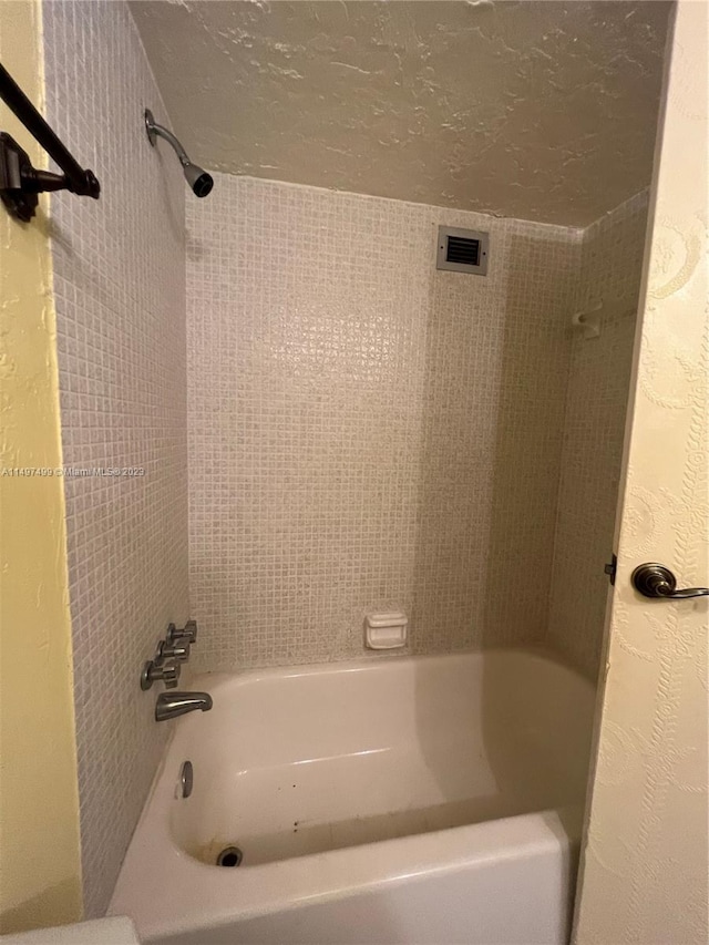 bathroom featuring tiled shower / bath combo and a textured ceiling