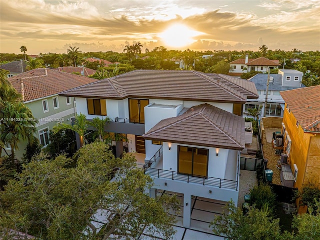 view of front of house featuring a balcony, stucco siding, a residential view, and a tiled roof