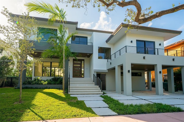 rear view of house with a balcony, stairway, a lawn, and stucco siding