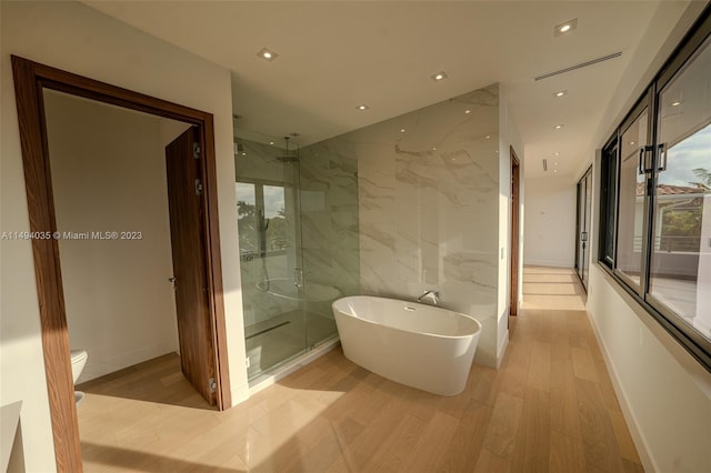 full bath featuring a freestanding bath, a stall shower, wood finished floors, and toilet