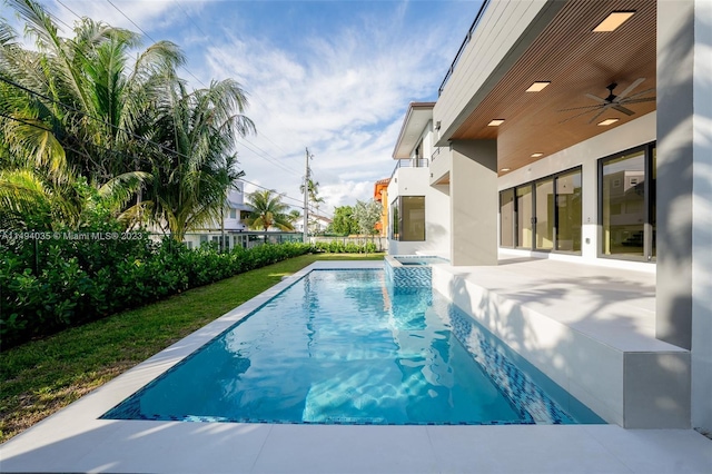 view of swimming pool featuring a pool with connected hot tub, a patio area, ceiling fan, and fence