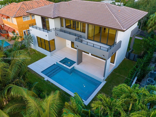 back of house with a fenced backyard, a patio area, a balcony, and stucco siding