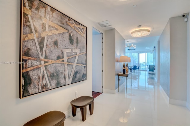 corridor with an inviting chandelier and tile patterned flooring