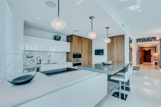 kitchen with sink, white cabinetry, decorative light fixtures, black electric stovetop, and decorative backsplash