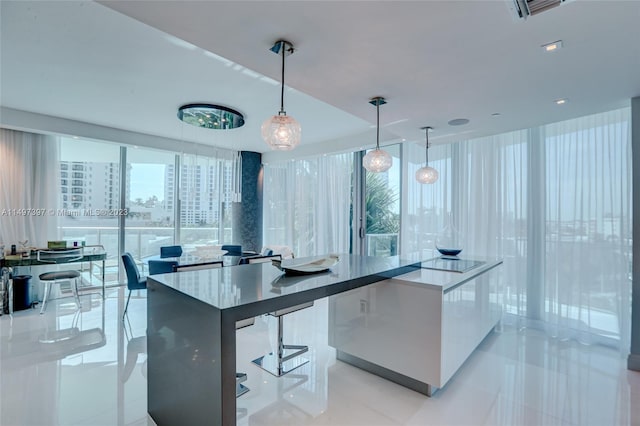 kitchen featuring hanging light fixtures, light tile patterned flooring, expansive windows, and a breakfast bar area