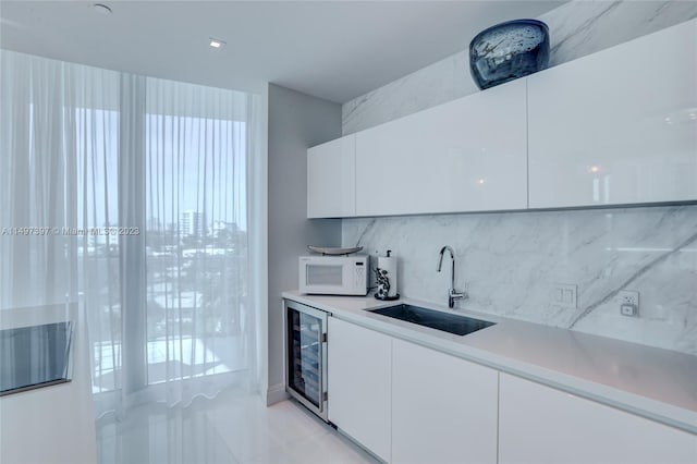 kitchen with tasteful backsplash, beverage cooler, sink, and white cabinets