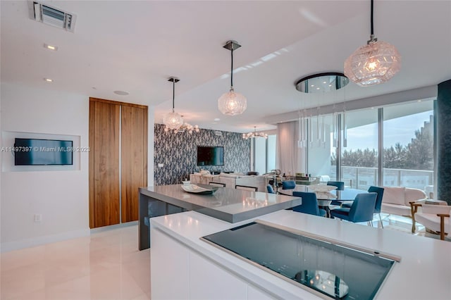 kitchen featuring a notable chandelier, decorative light fixtures, white cabinets, and light tile patterned flooring