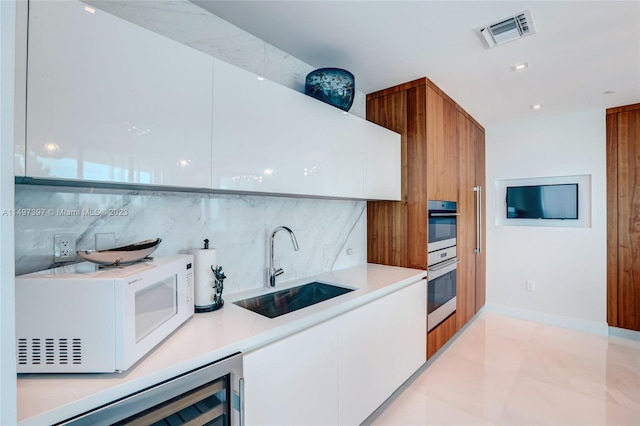 kitchen with sink, white cabinets, backsplash, and double oven