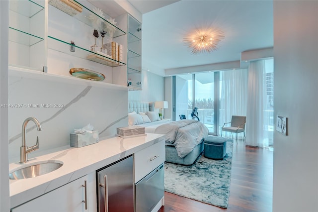 bedroom featuring high end fridge, sink, dark wood-type flooring, and a wall of windows