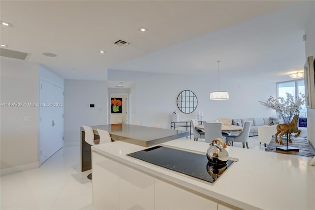 kitchen featuring black electric cooktop, white cabinetry, hanging light fixtures, and light tile patterned floors