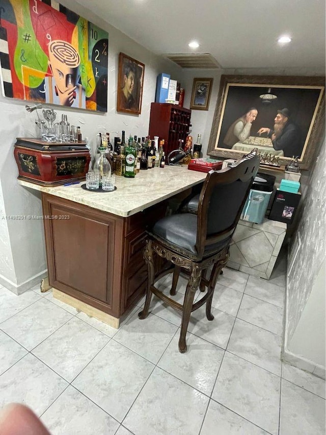 bar featuring dark brown cabinets and light tile floors