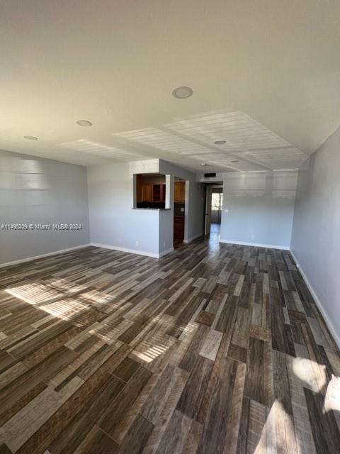 unfurnished room with dark wood-type flooring