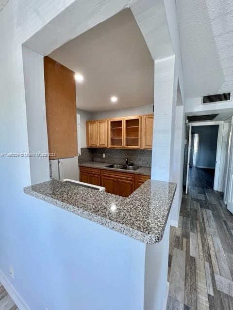 kitchen featuring sink, hardwood / wood-style floors, tasteful backsplash, and stone countertops