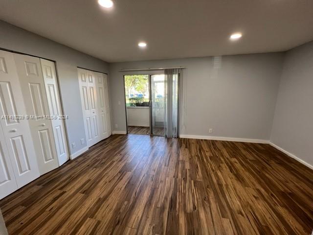 unfurnished bedroom featuring two closets and dark hardwood / wood-style floors