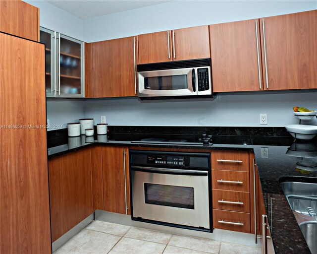 kitchen featuring brown cabinets, dark stone countertops, and stainless steel appliances