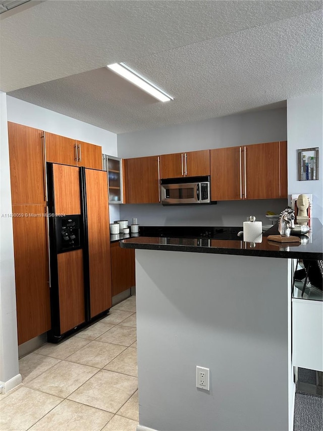 kitchen with stainless steel microwave, high end refrigerator, dark countertops, a peninsula, and brown cabinets