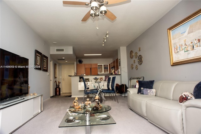living area featuring ceiling fan, visible vents, and light carpet