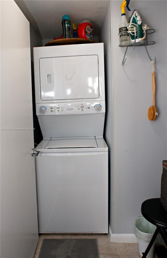 clothes washing area with stacked washer / dryer, laundry area, and light tile patterned floors