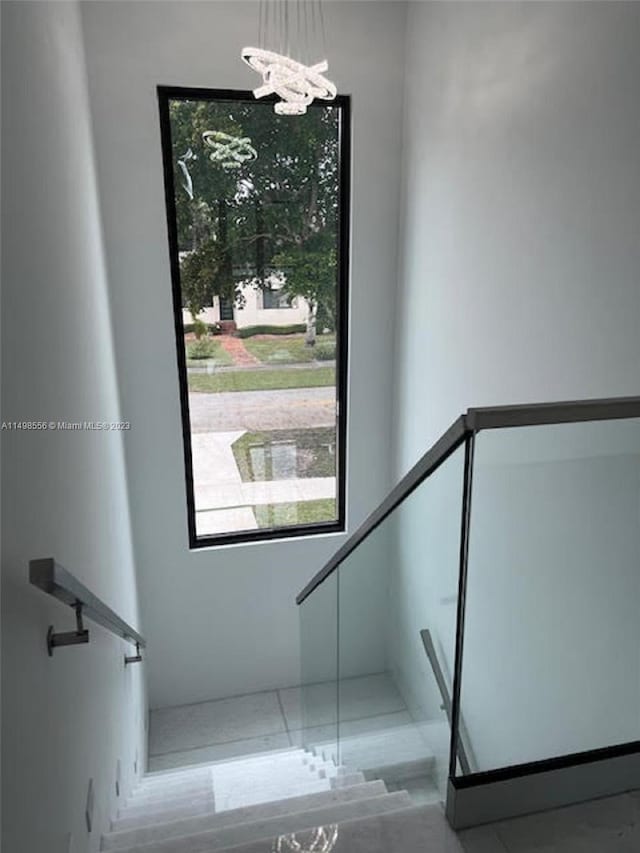 staircase with an inviting chandelier