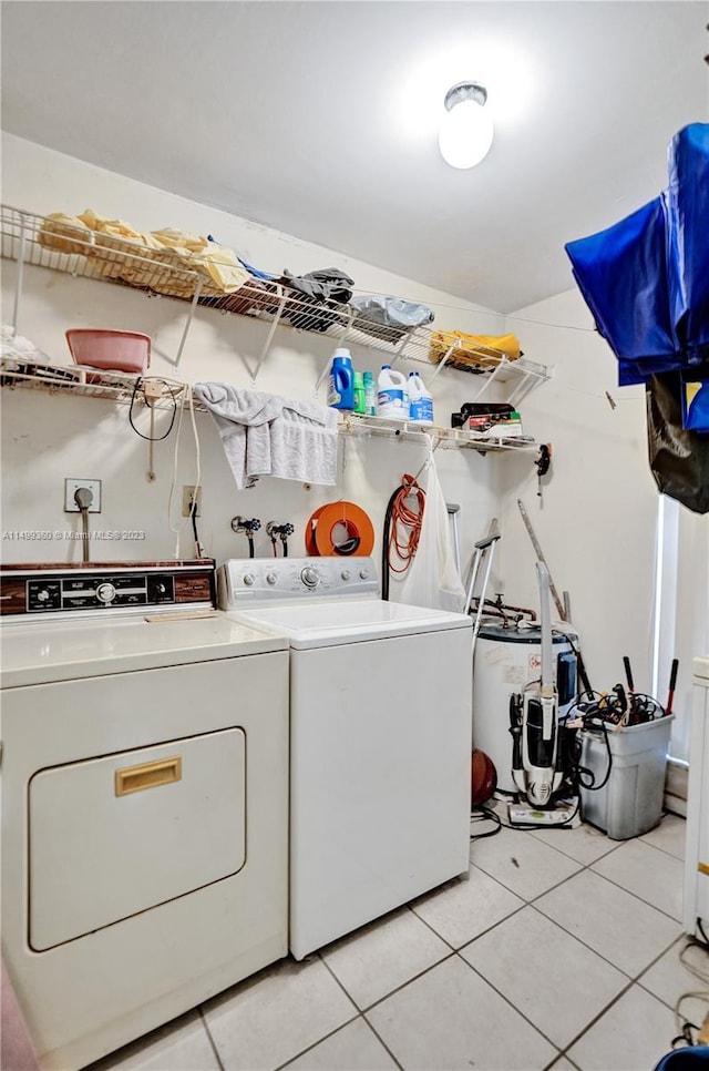 washroom with water heater, light tile patterned flooring, and washing machine and clothes dryer