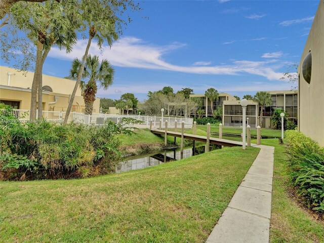 view of dock with a yard and a water view