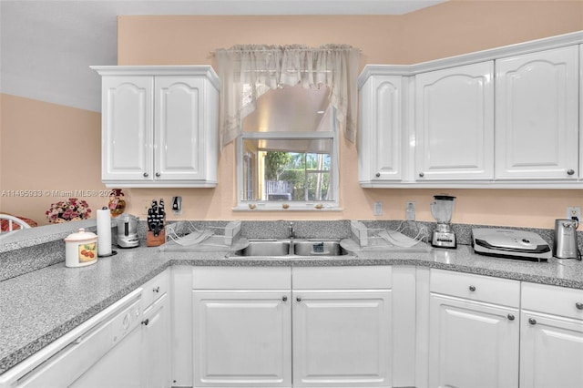 kitchen with white cabinets, light stone counters, dishwasher, and sink