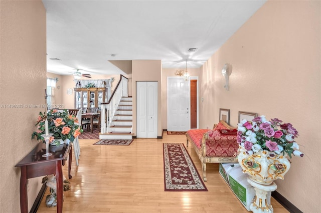 foyer with ceiling fan with notable chandelier and light wood-type flooring