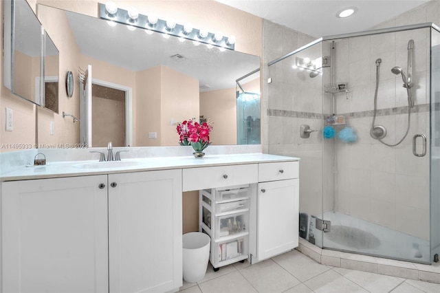 bathroom with tile floors, a shower with shower door, and vanity